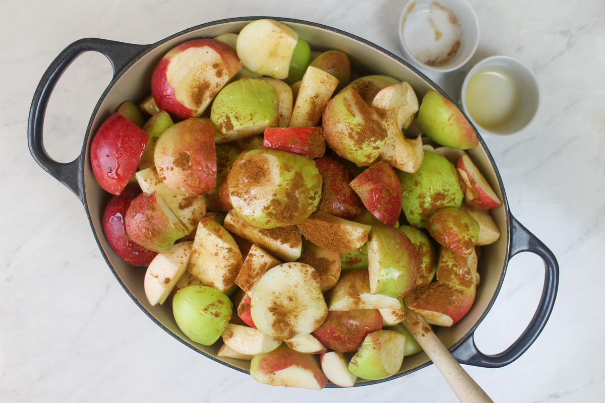 A large pot of apples sprinkled with cinnamon and honey, ready to cook.