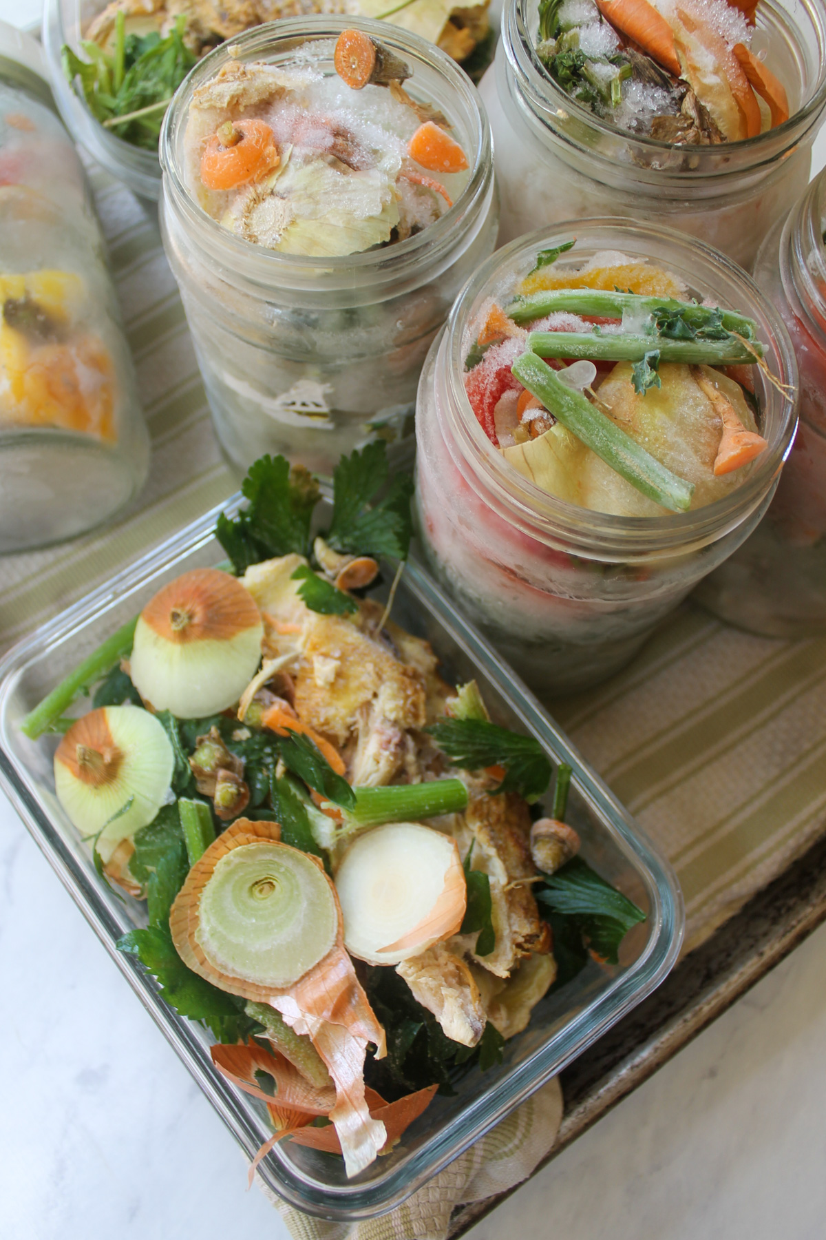 Glass containers of chicken bones and vegetable scraps that have been frozen to make stock.