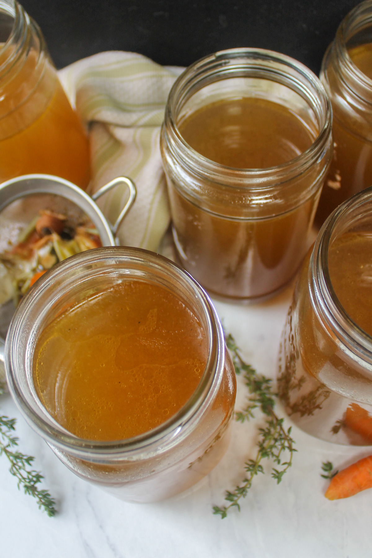 Top down view of jars of golden brown chicken stock made from kitchen scraps.