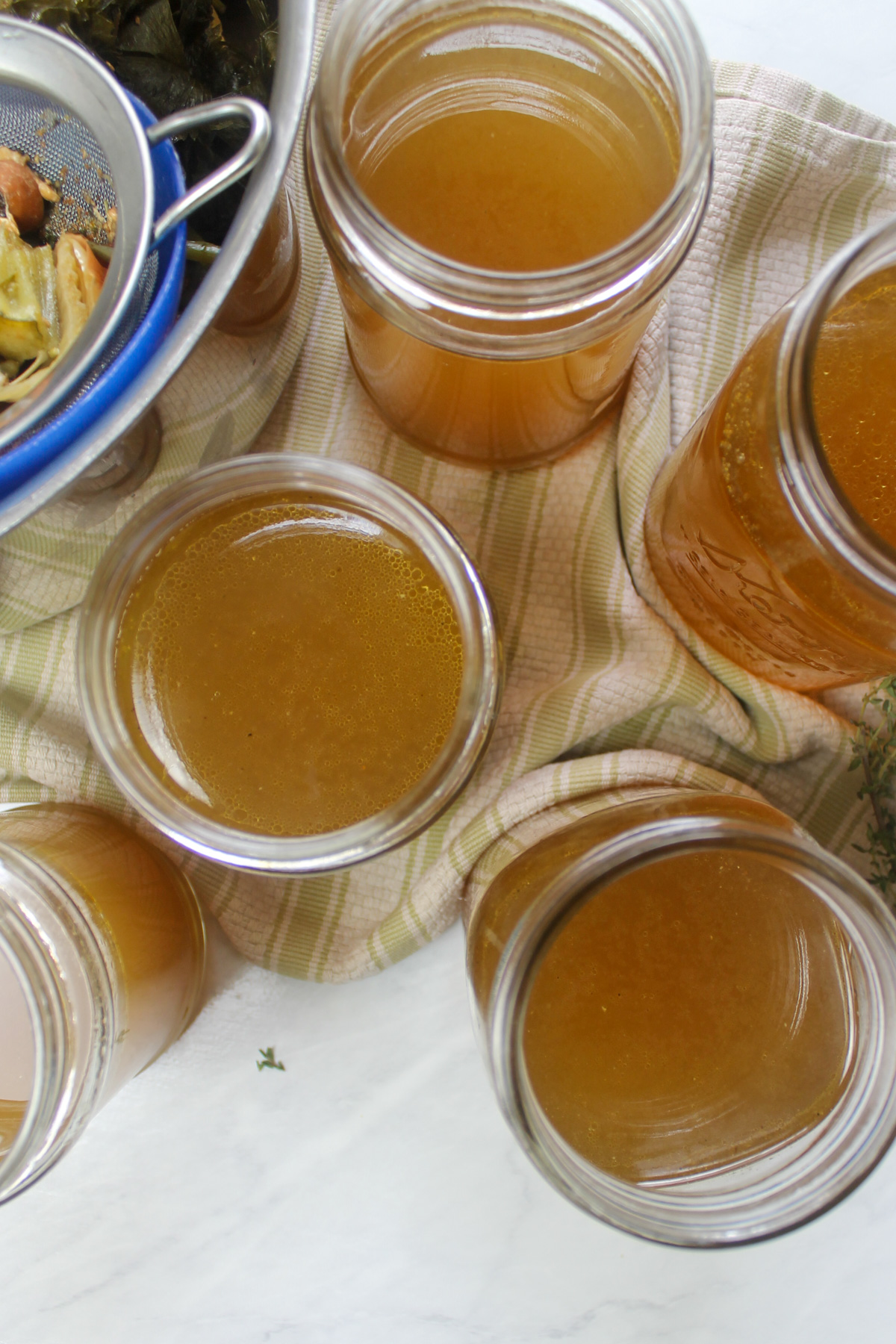 Top down view of jars of golden brown chicken stock made from kitchen scraps.