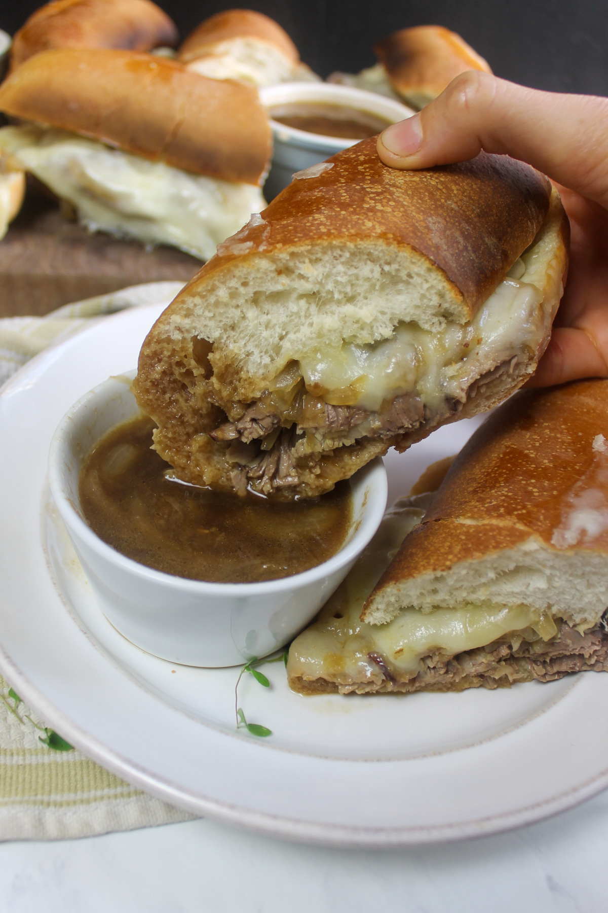 A French dip sandwich, dunked in a cup of au jus sauce.