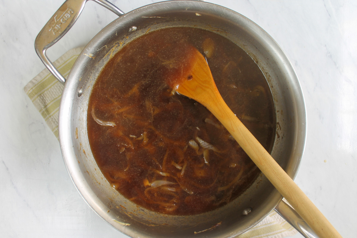 Beef stock added to caramelized onions to make au jus sauce.