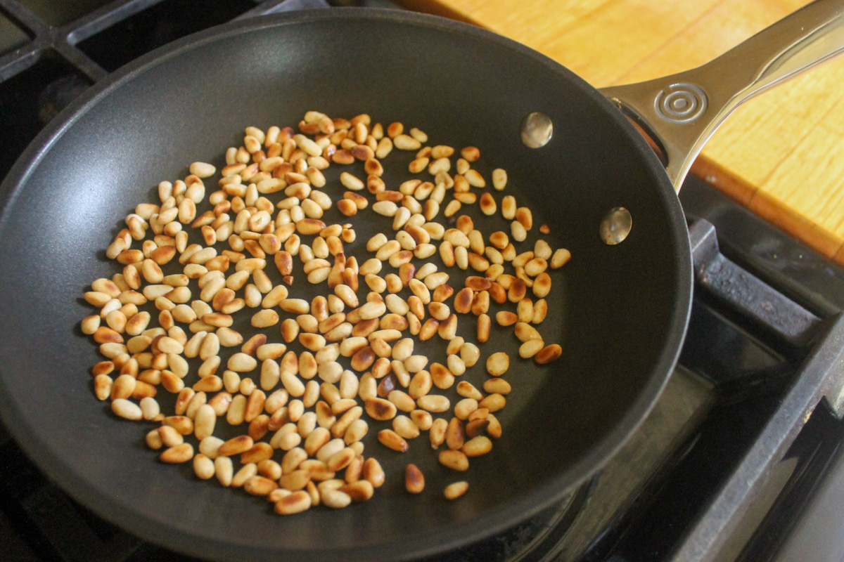 Toasting pine nuts in a small pan.