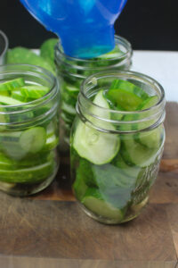 Jars full of sliced cucumbers ready to pour in the hot vinegar brine.