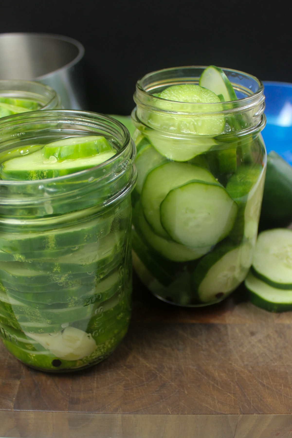 Hot brine added to jars of sliced cucumbers.