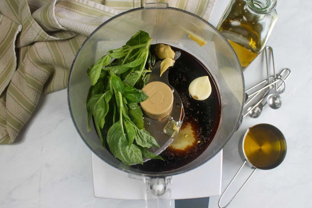 Basil vinaigrette vinaigrette ingredients in the bowl of a food processor.
