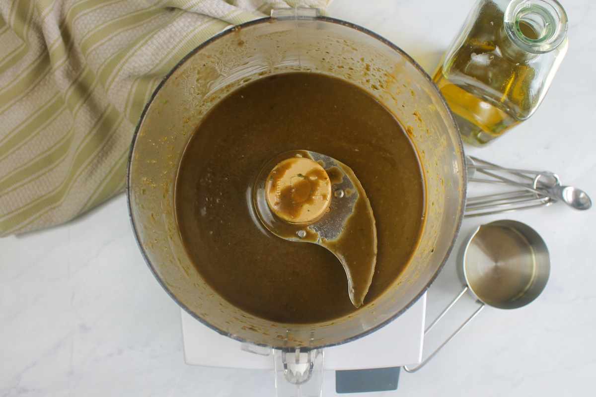 Blending basil balsamic vinaigrette in a food processor.