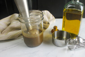 Blending a jar of balsamic vinaigrette dressing with an immersion blender.