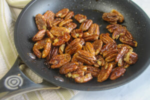 The finished candied pecans in a skillet.