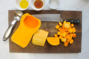 Chopping the butternut squash into cubes on a cutting board.