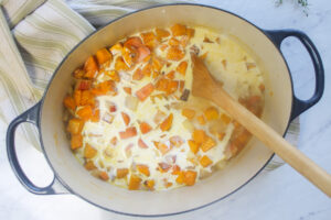 Adding cream to squash and carrot soup.