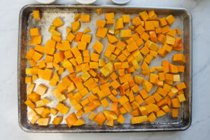 A sheet pan of cubed butternut squash ready to be roasted in the oven.