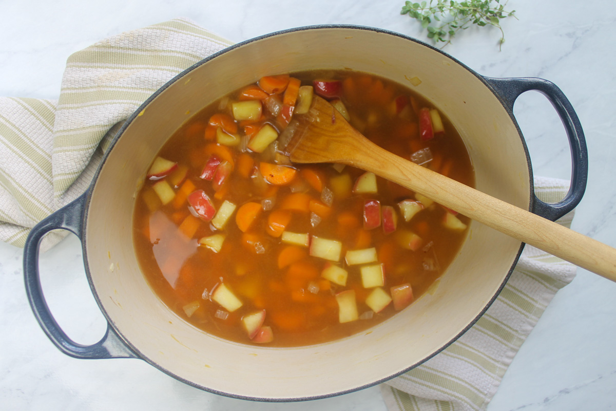 Adding the stock to the sautéed pot of veggies.