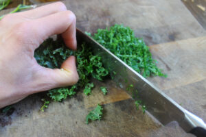 How to slice kale by tightly wadding it up and slicing it into thin shavings.