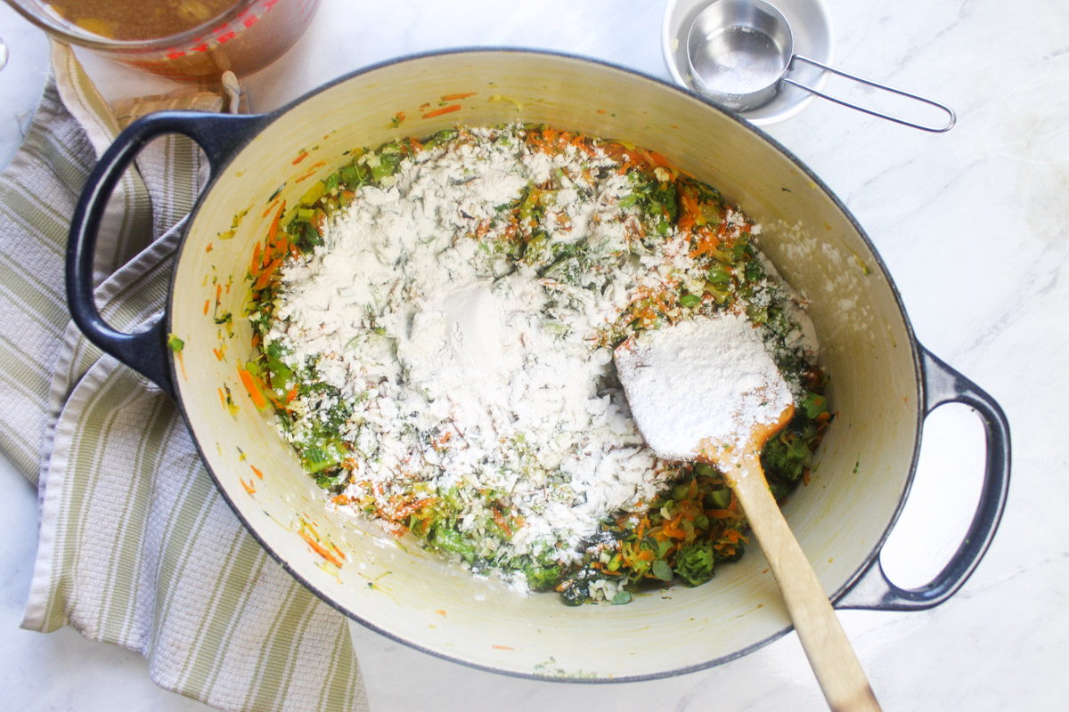 Adding flour to the cooked veggies as the thickener for the soup.