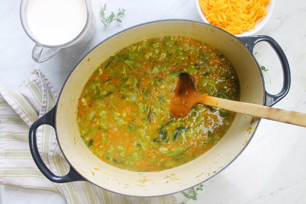 Adding stock to the zucchini broccoli soup.