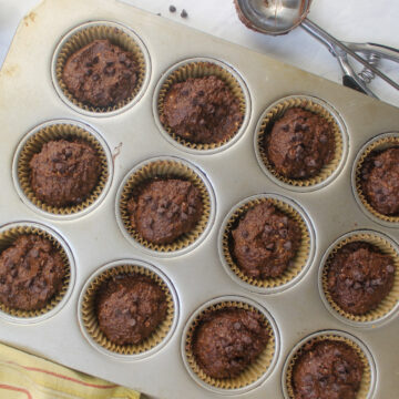 A muffin tin filled with chocolate pumpkin batter.