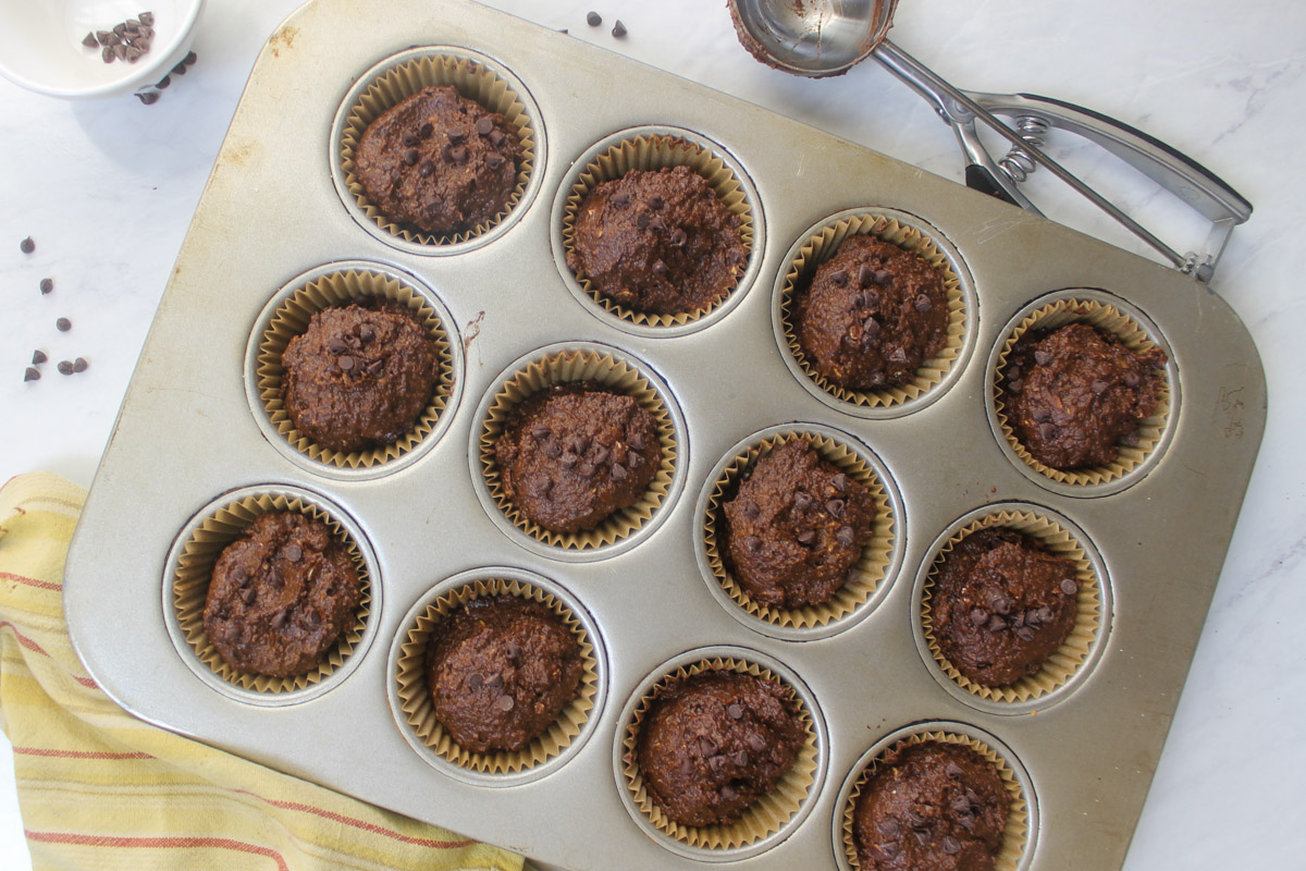 A muffin tin filled with chocolate pumpkin batter.
