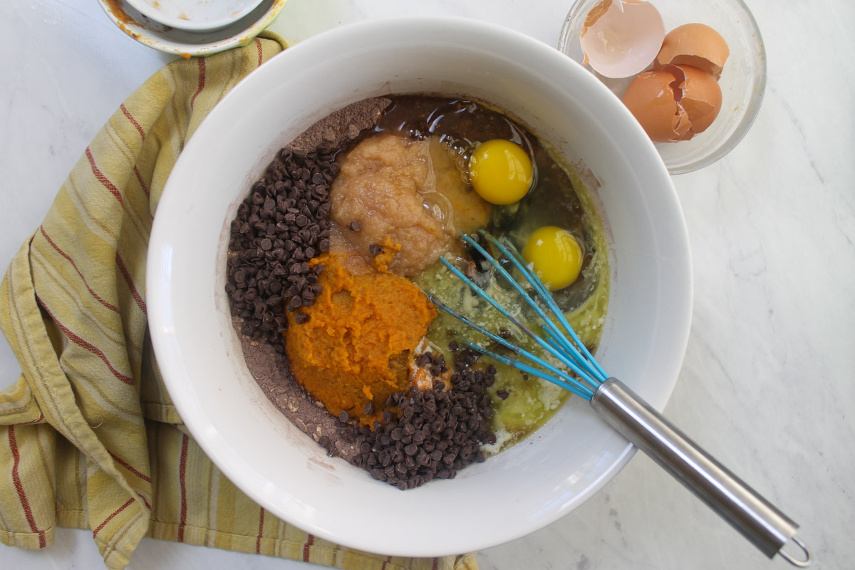 Adding all chocolate pumpkin muffin ingredients to a mixing bowl.