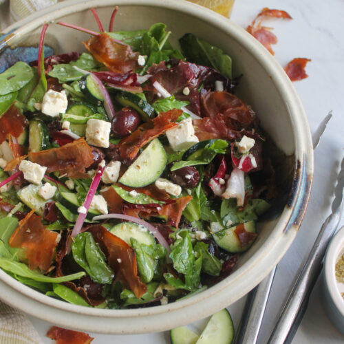 A bowl of Italian salad with mixed greens, kalamata olives and crispy prosciutto.