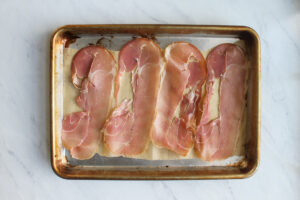 Prosciutto laid out on a baking sheet with parchment paper.