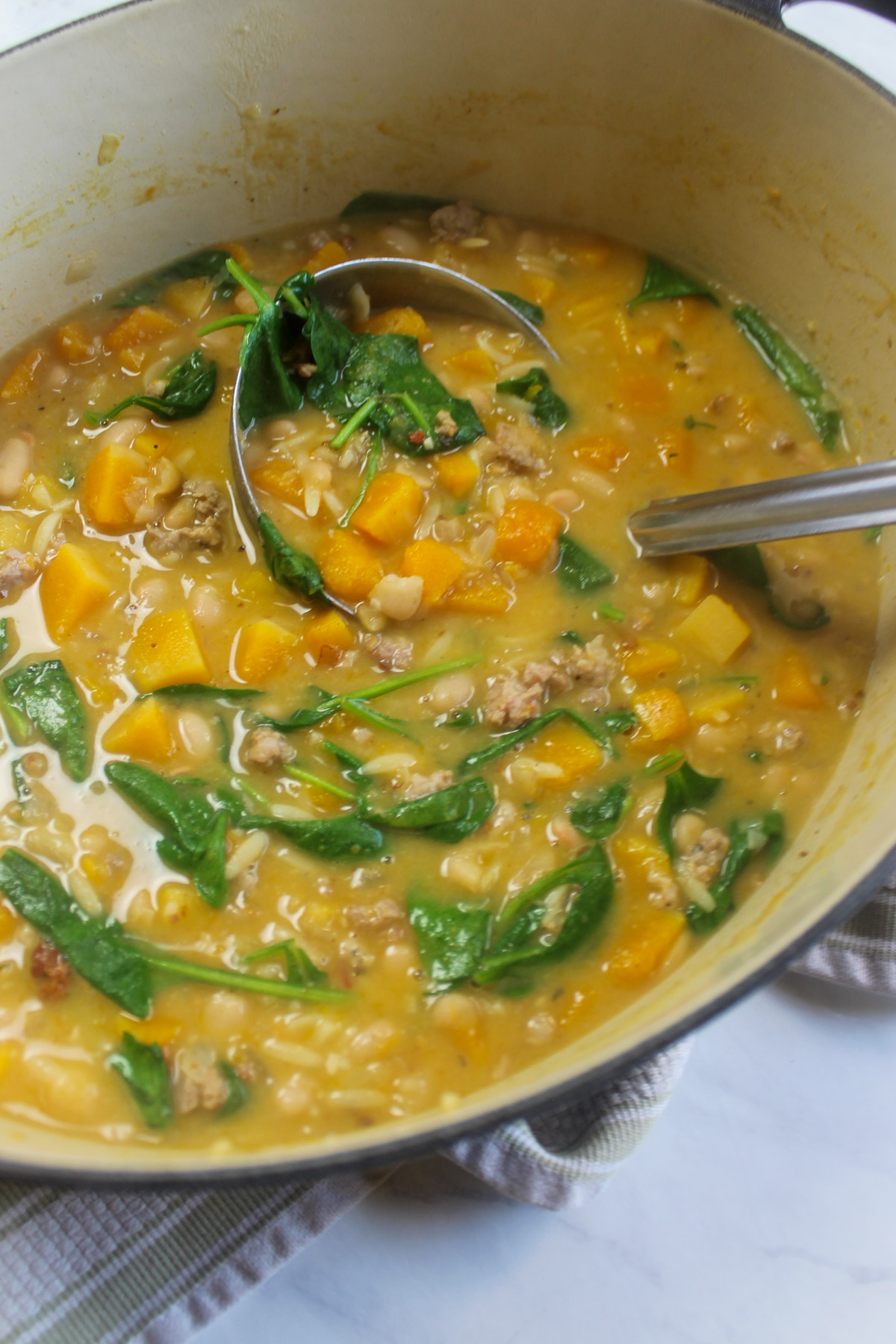 A pot of butternut squash and white bean soup with spinach.