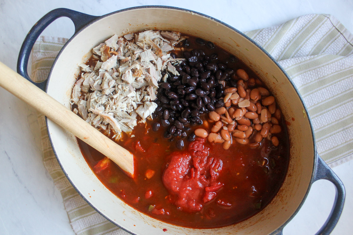 Adding all ingredients to the pot of turkey chili.