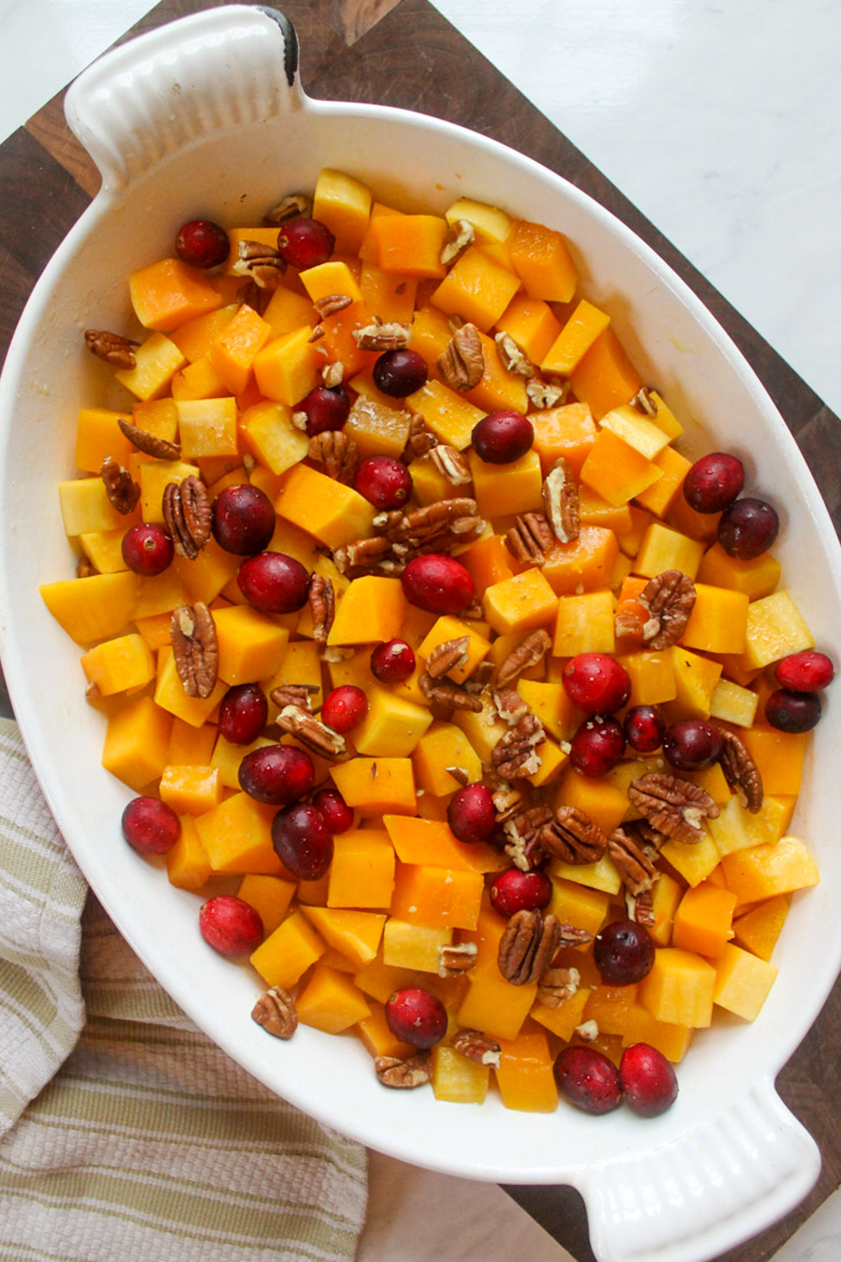 Adding the cranberries and pecans to the par-baked butternut squash.