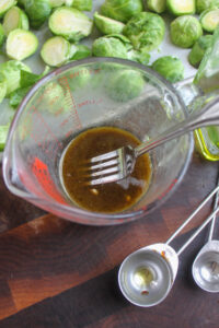 A glass measuring cup of glaze made of butter, honey, oil and balsamic vinegar.
