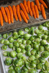 Carrots and Brussel sprouts tossed in glaze and spread on 2 sheet pans cut side down.