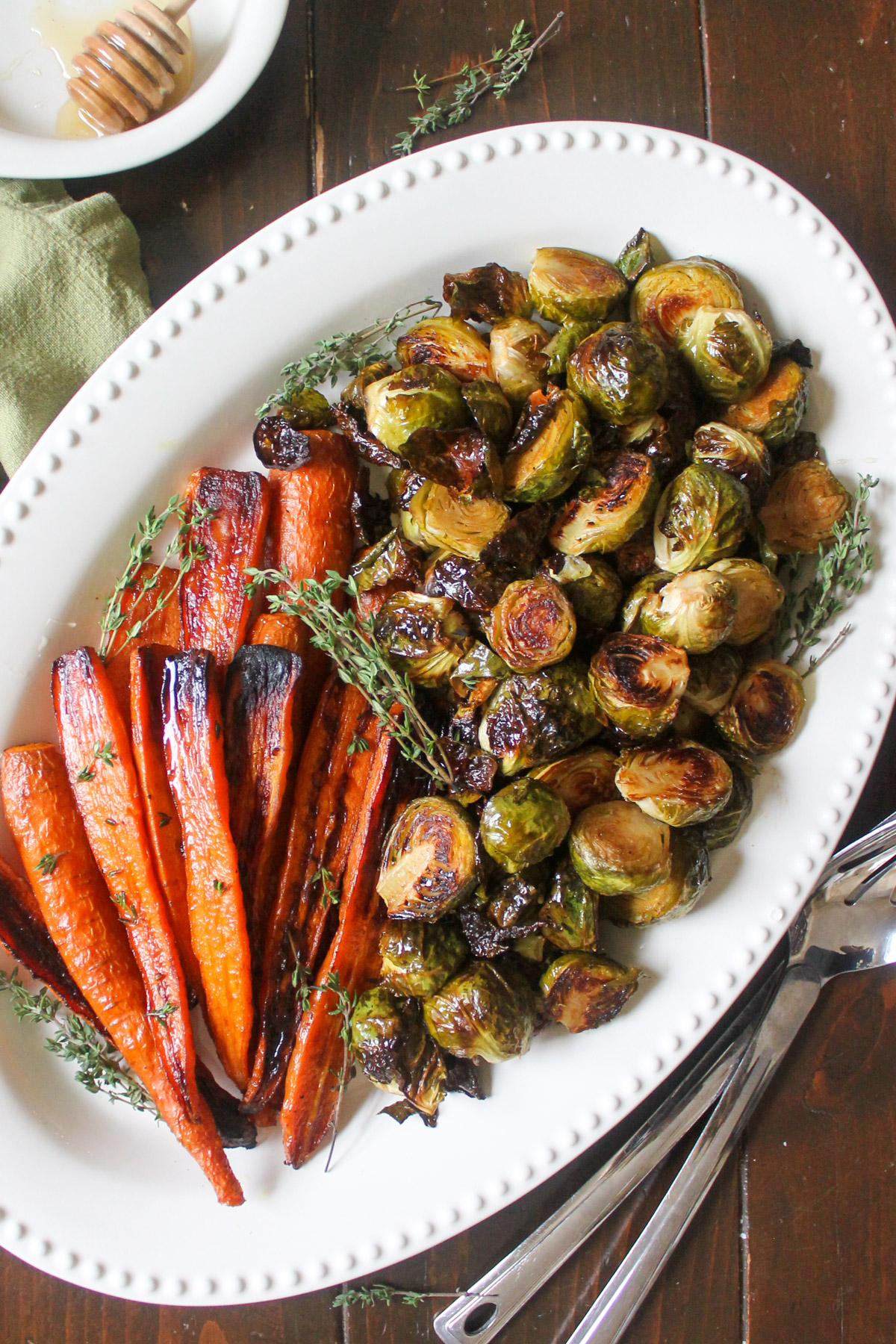 A large party platter side dish of roasted Brussel sprouts and carrots with fresh thyme.