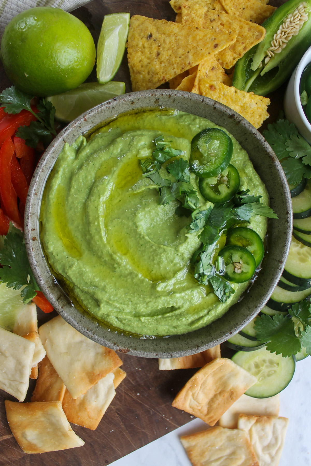 A bowl of cilantro lime hummus with pita crackers and veggies.
