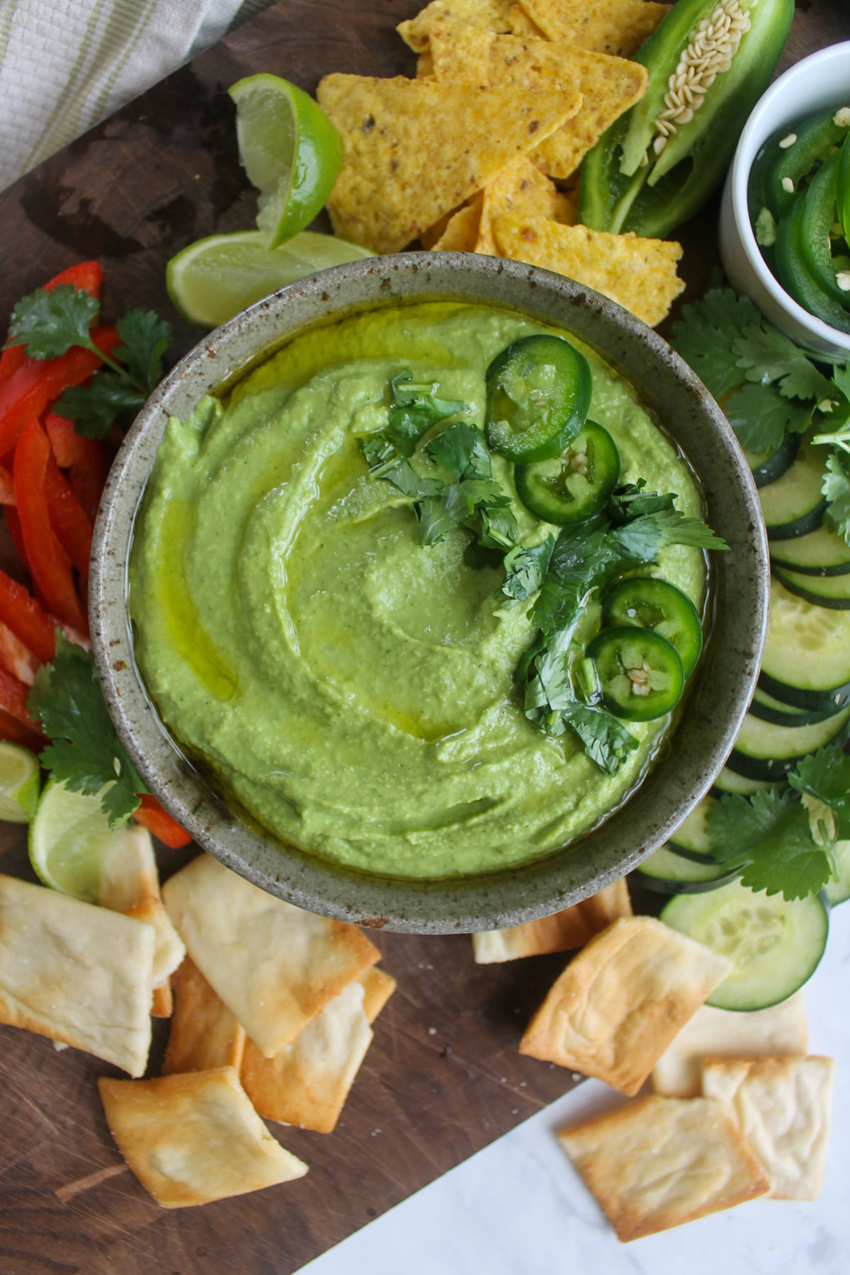Jalapeño cilantro hummus with chips, bell peppers, cucumber and pita crackers to dip.