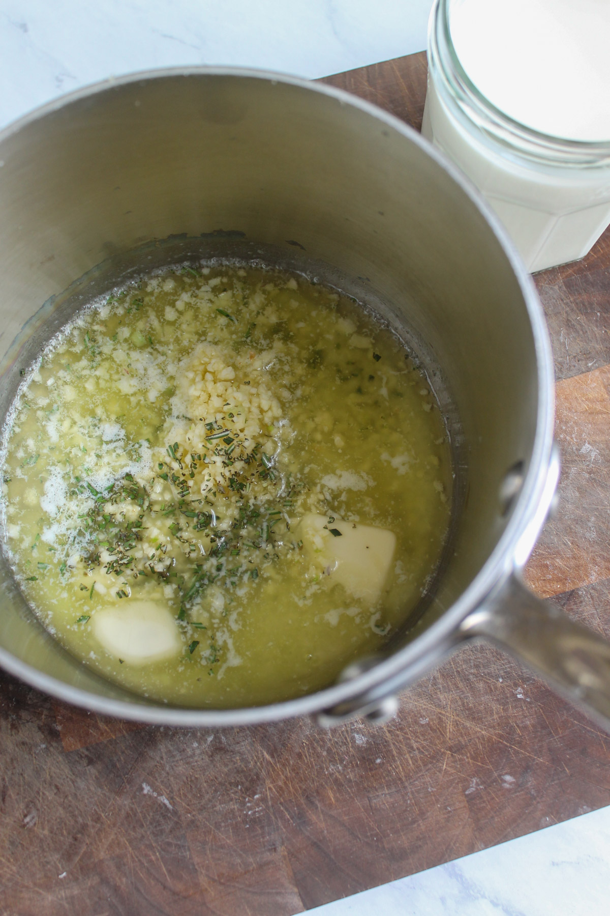 A small saucepan of melted butter with garlic and fresh rosemary to flavor mashed potatoes.