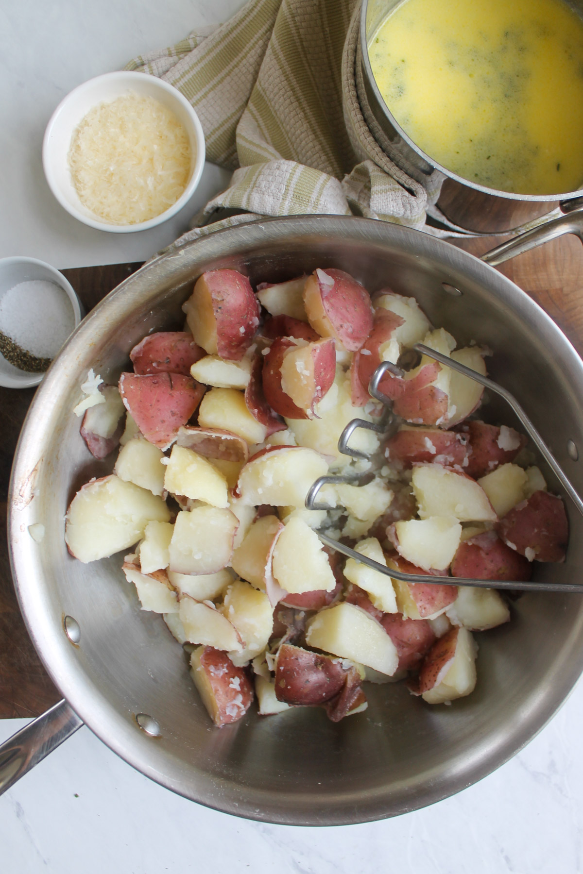 A pot of drained boiled potatoes ready to add garlic herb butter and half and half to mash.