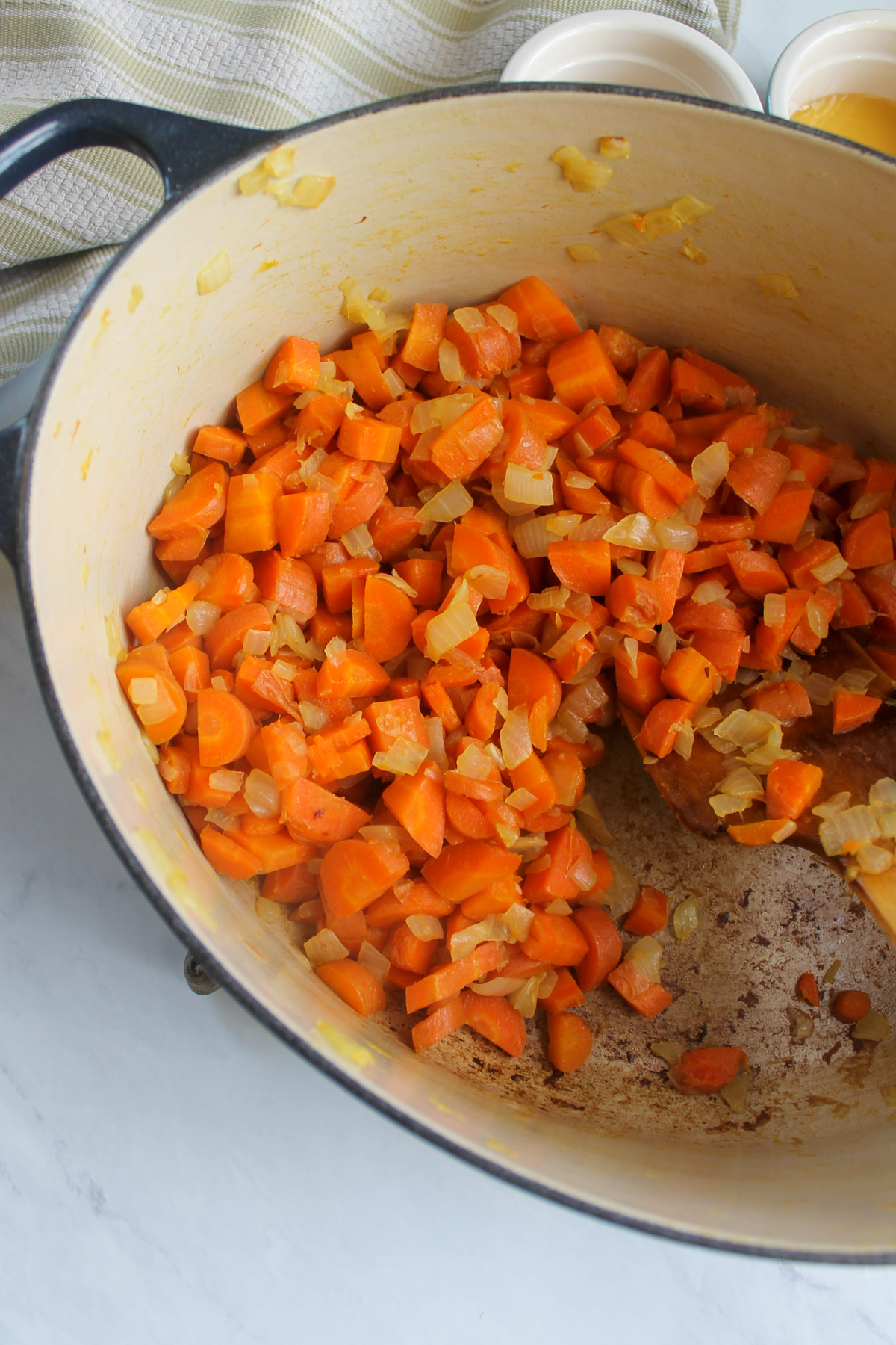 A Dutch oven with sautéed carrots and onion.