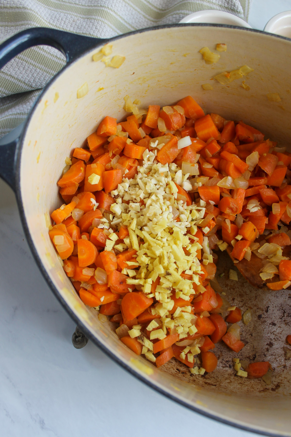 Adding fresh minced ginger and garlic to the carrots and onion.