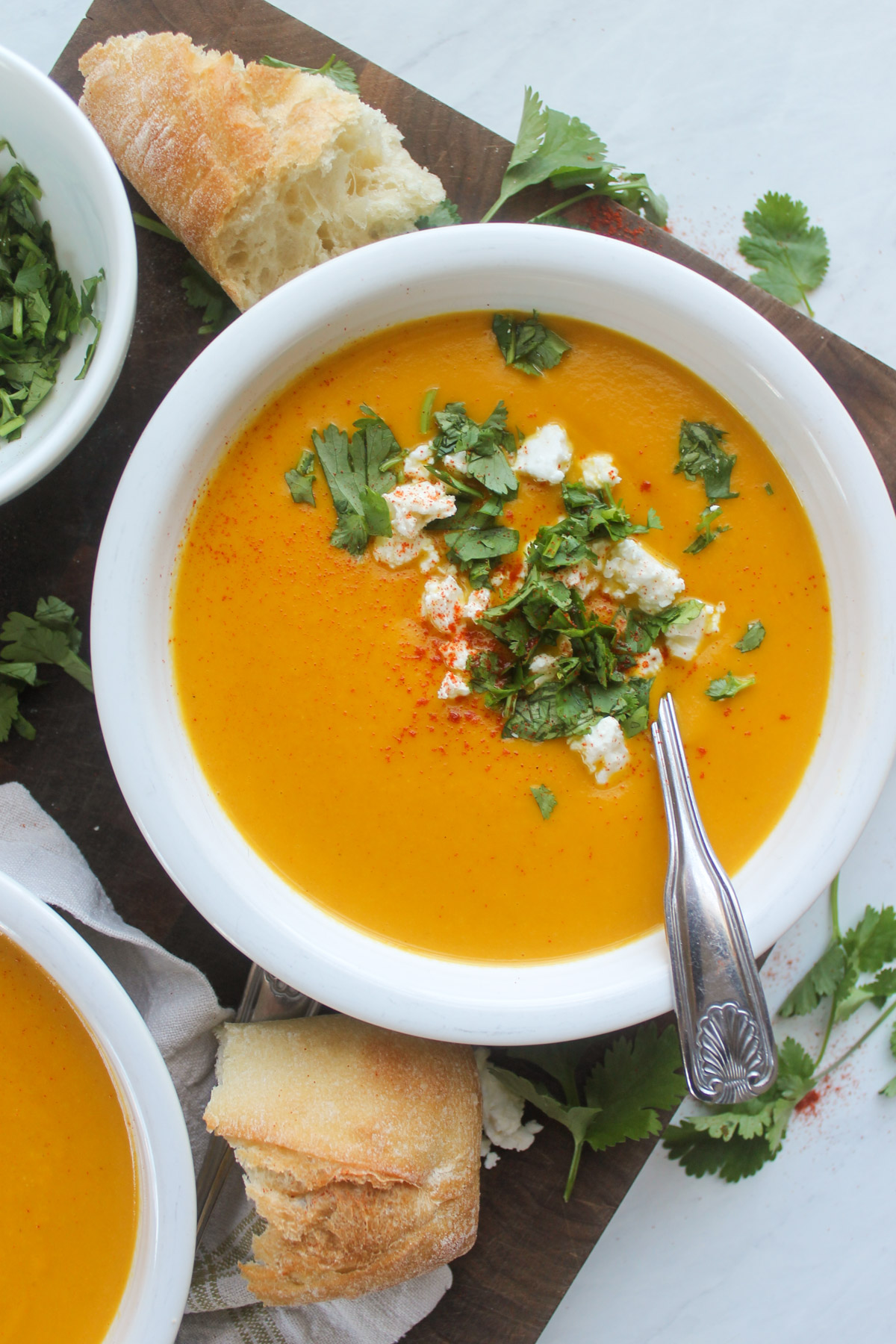 A white bowl of Carrot ginger coconut soup with chickpeas.