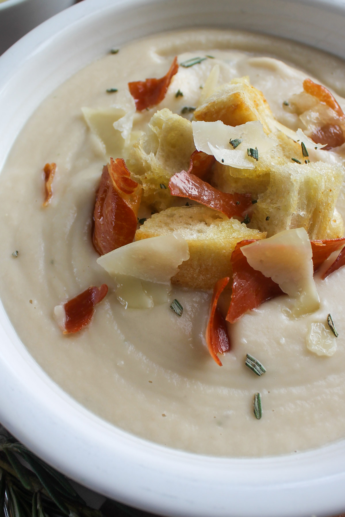 A close up of a bowl of creamy cauliflower soup with white beans.
