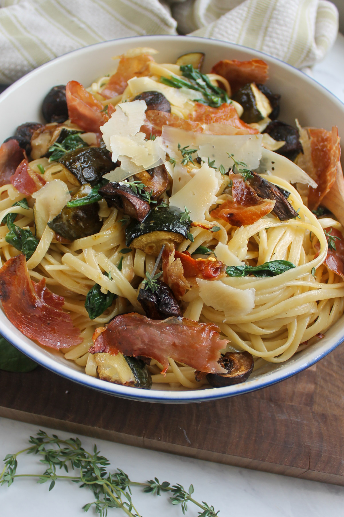 A bowl of linguine pasta with zucchini and mushrooms in cream sauce.