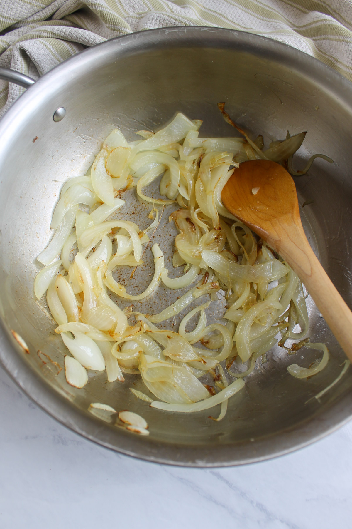 Onion slices beginning to caramelize in a skillet.