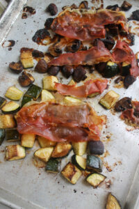 Roasted zucchini and mushrooms topped with the crispy prosciutto on a sheet pan hot from the oven.