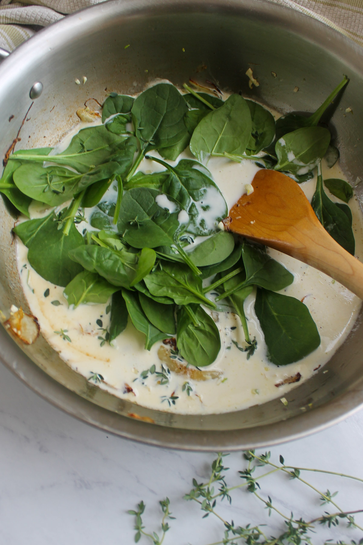 Adding raw spinach to wilt into the caramelized onion cream sauce.