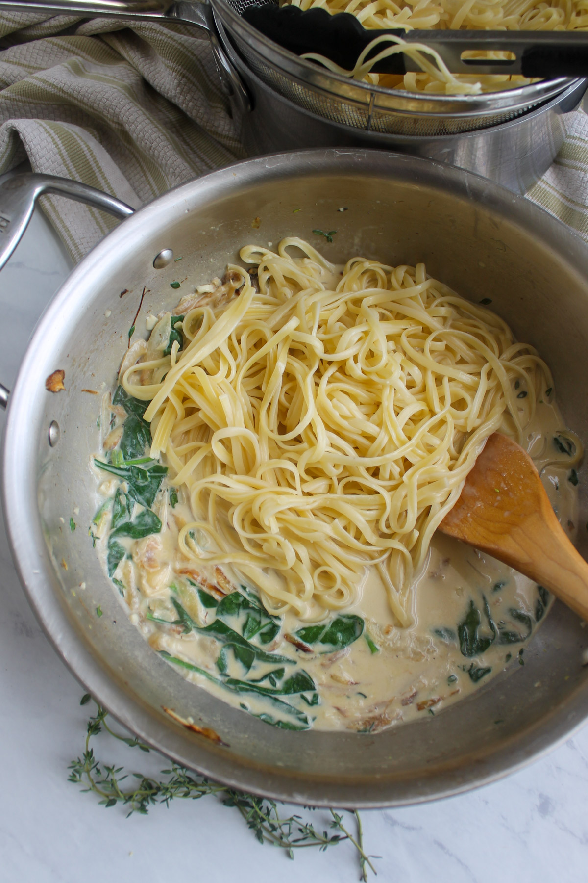 Adding the linguine to toss with the cream sauce.