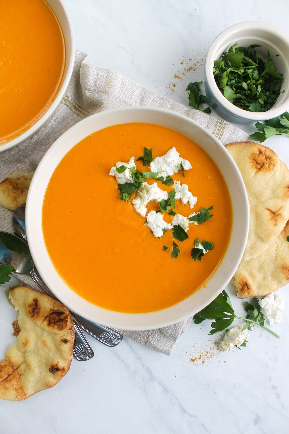 Bowls of butternut squash orange and ginger soup with naan bread.