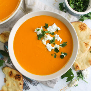 A bowl of butternut squash and red pepper soup with ginger and coconut.