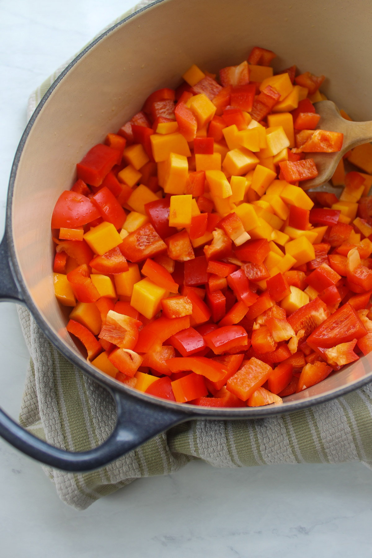 A soup pot full of chopped butternut squash and red bell peppers.