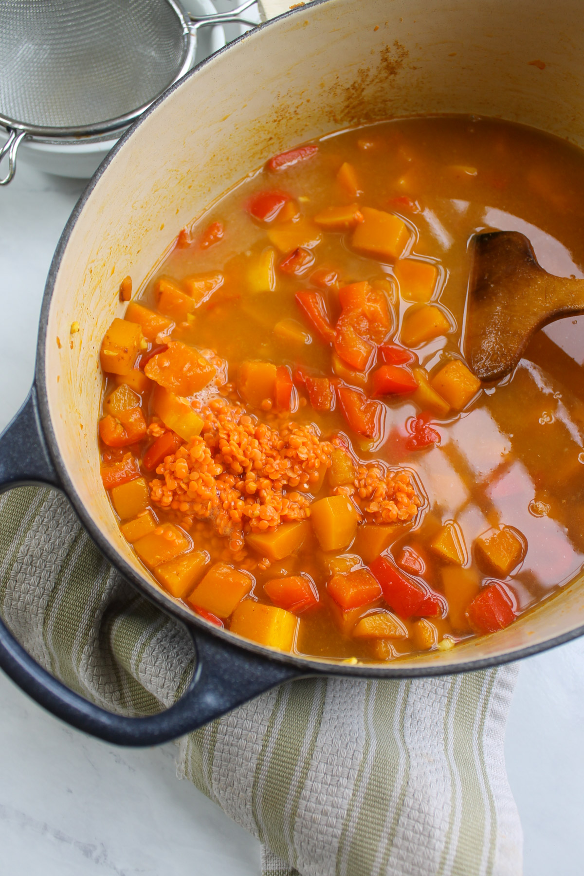 Adding red lentils to butternut squash red pepper soup.