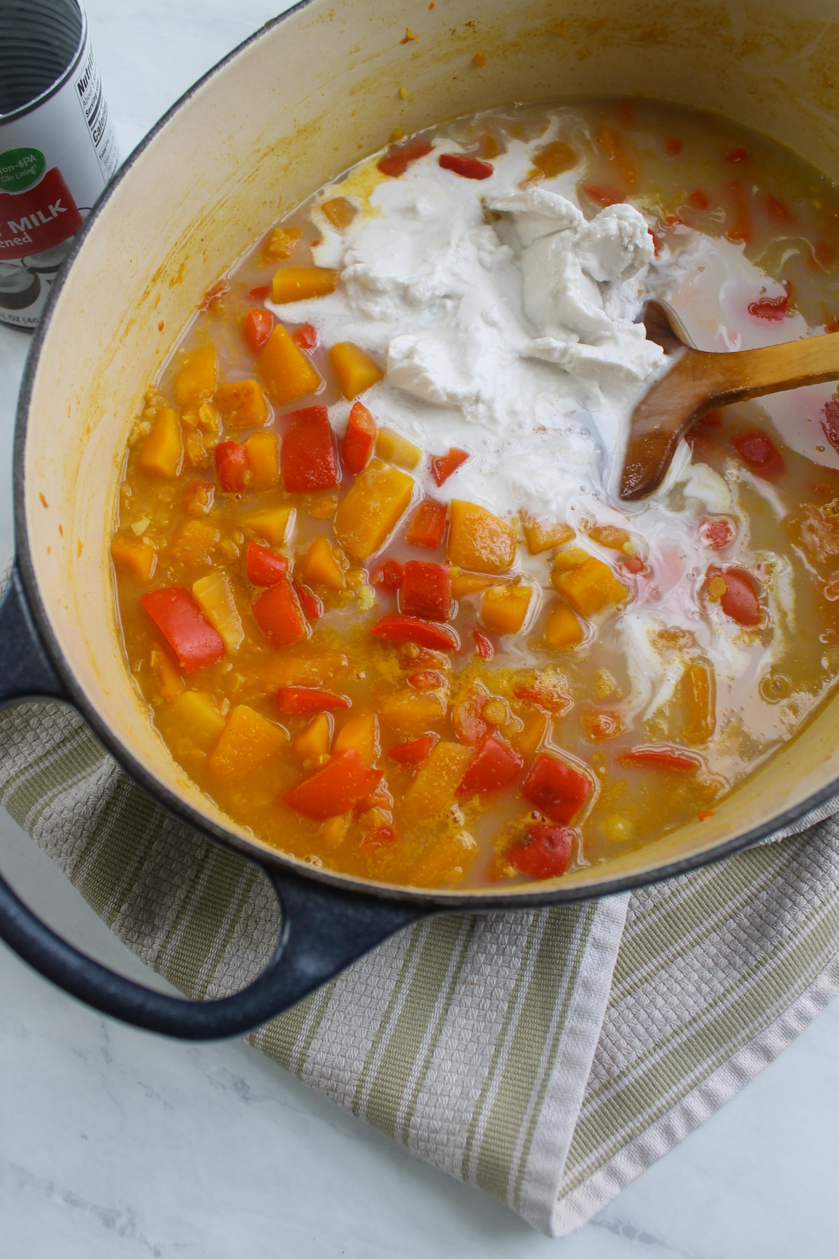 Adding a can of coconut milk to butternut squash and red pepper soup.