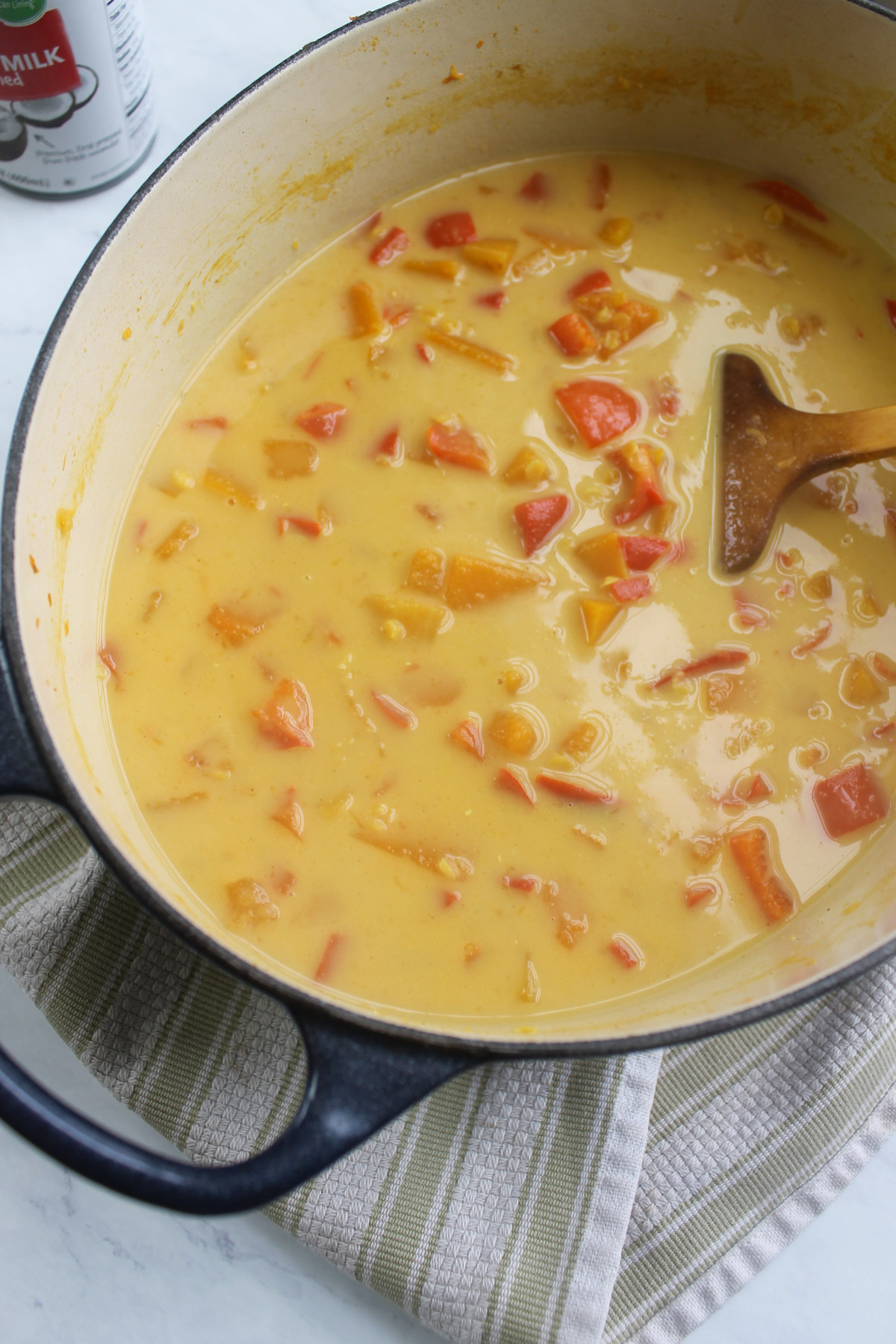 A soup pot full of butternut squash soup with coconut milk that has not yet been blended.